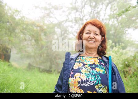 Una donna ispanica matura e attiva sorride volentieri guardando la macchina fotografica, godendosi una passeggiata mattutina nella natura, vicino a Barichara, Colombia. Foto Stock