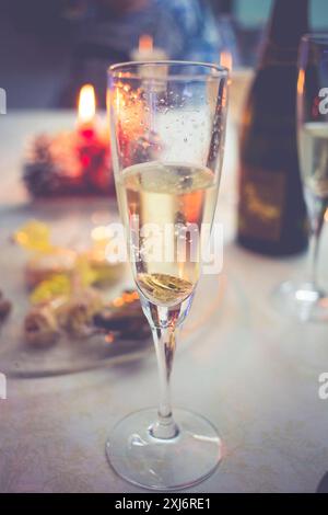 Primo piano di un bicchiere di champagne su un tavolo con tartine e una candela Foto Stock