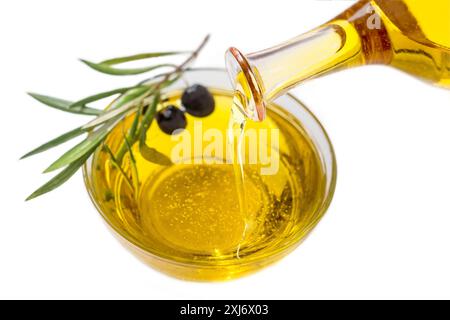 Versare l'olio d'oliva in un piccolo recipiente su sfondo bianco Foto Stock