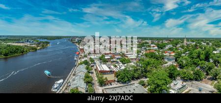 Vista panoramica aerea del quartiere storico di Wilmington, North Carolina, lungo il fiume Cape Fear, con la nave da battaglia del North Carolina con il cielo nuvoloso Foto Stock