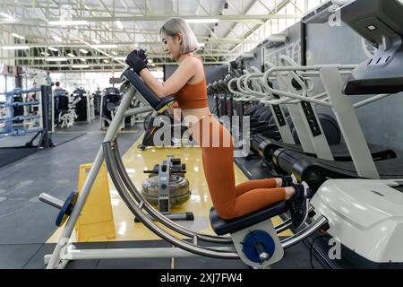 Giovane donna che usa la macchina da coaster ab durante il suo esercizio mattutino in una palestra locale Foto Stock