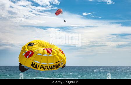 Paracadute colorato per paracadutismo ascensionale con persone a Phuket Beach in Thailandia durante l'estate. Persone con paracadute sullo sfondo blu del cielo. Parasailing. Estate t Foto Stock