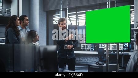 Gruppo di sviluppatori di software multietnici che tengono una riunione in una sala conferenze con schermo verde. Specialisti indiani brainstorming nuove idee e risoluzione dei problemi in ufficio Foto Stock
