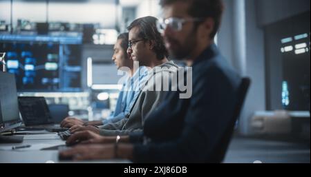 Giovane appassionato Specialista che lavora su computer, programmazione di un software per un lancio di prodotti Internet tecnologici innovativi. Squadra indiana diversificata che lavora in una Startup Agency Foto Stock