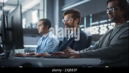 Giovane appassionato Specialista che lavora su computer, programmazione di un software per un lancio di prodotti Internet tecnologici innovativi. Squadra indiana diversificata che lavora in una Startup Agency Foto Stock