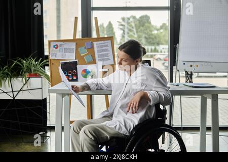 Una giovane donna d'affari in sedia a rotelle siede a una scrivania in un ufficio moderno, rivedendo i documenti. Foto Stock