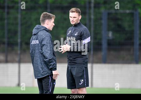 Landore, Swansea, Galles. 13 luglio 2024. Sam Morris Swansea City Academy Professional Development Phase Analyst (a destra) parla con Liam McGarry Swansea City Academy Head of Coaching a metà tempo durante l'amichevole tra Swansea City ed Exeter City alla Swansea City Academy di Landore, Swansea, Galles, Regno Unito, il 13 luglio 2024. Crediti: Duncan Thomas/Majestic Media. Foto Stock