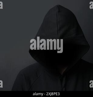 Buio, felpa con cappuccio e hacker in studio, nascosto e sotto copertura per stalking, persona e ladro con crimine. Sfondo nero, truffa e criminale con pericolo Foto Stock
