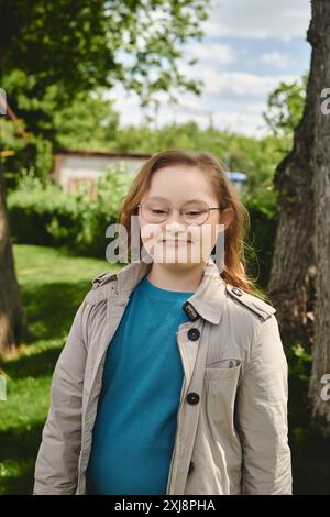 Una bambina con la sindrome di Down sta fuori casa, sorridendo in modo luminoso. Foto Stock