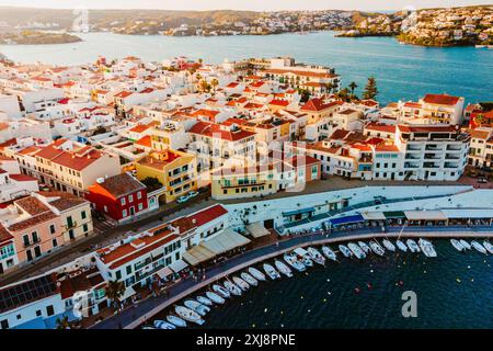 Vista aerea della cittadina tradizionale di es Castell sulla costa di Minorca con porto e barche al tramonto durante la stagione turistica estiva. Pittoresco traino baleari Foto Stock