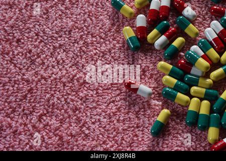 Primo piano della capsula bianca rossa e dei medicinali gialli verdi su sfondo rosso. Medicina per il dolore venoso. Foto Stock