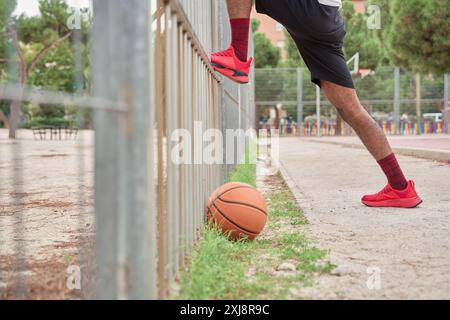 Giovane cestista afroamericano irriconoscibile che si allunga le gambe prima di giocare Foto Stock