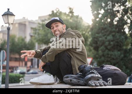 Ritratto di un giovane con pattini a rotelle in città seduti e sorridenti Foto Stock