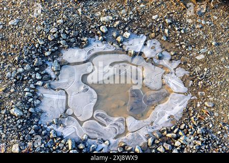 pozzetto d'acqua congelato con bolle d'aria su un percorso di ghiaia Foto Stock