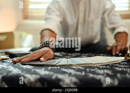 Primo piano di un indovino che distribuisce carte Tarocchi disposte su un tavolo ricoperto di tessuto mistico Foto Stock