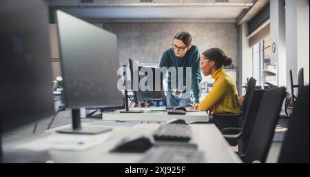 Team multietnico di due studenti che chattano in classe informatica, preparandosi per gli esami a scuola. Giovani sviluppatori di software che parlano della creazione di un progetto di ricerca online sulla sicurezza ai Foto Stock