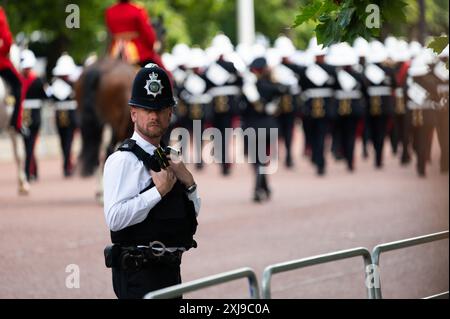 Londra, Regno Unito. 17 luglio 2024. Un agente di polizia che tiene d'occhio la folla mentre i membri della guardia domestica marciano lungo il centro commerciale. L'apertura statale del Parlamento è un evento cerimoniale che segna l'inizio di un nuovo parlamento, ed è l'unica occasione regolare in cui il sovrano, la camera dei lord e la camera dei comuni si incontrano. Crediti: David Tramontan / Alamy Live News Foto Stock