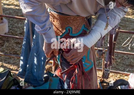 Un cowboy di rodeo indossa i suoi pantaloni di pelle prima del suo giro in bronzo nudo in un rodeo in una piccola città dello Utah. I polsini in pelle offrono un gri più frizionale Foto Stock