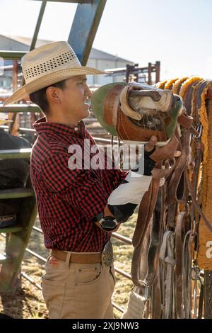 Un cowboy di rodeo Navajo con un gomito a gomito si fa vestire da bareback per indossare un cavallo da corsa prima di andare in un rodeo nello Utah. Foto Stock