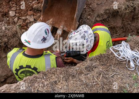 Lavoratori che installano tubi protettivi in plastica per cavi in fibra ottica per Internet sotterranei nello Utah rurale. Foto Stock