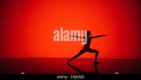 Young Girl si impegna in pose pacifiche su uno sfondo Digital Red, incanalando l'equilibrio interiore e l'armonia con movimenti aggraziati ed espressioni tranquille. Pratica di yoga cinematografico Foto Stock