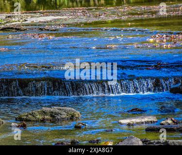 Il torrente scorre dolcemente sopra piccole cascate e isole rocciose Foto Stock