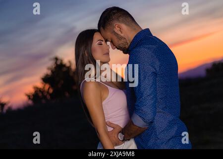 Un uomo e una donna abbracciano durante un tramonto vibrante. Foto Stock