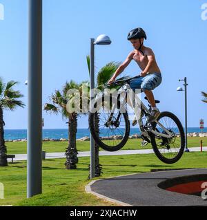 Un ragazzo che esegue una acrobazia con una bicicletta in uno skate Park a Tel Aviv, Israele Foto Stock