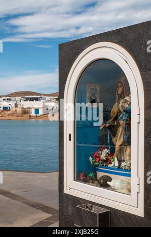 Santuario con una statua della Vergine Maria in un porto. Oceano Atlantico, case della città e una collina sullo sfondo. Cielo blu con nuvole bianche. Caleta del Foto Stock