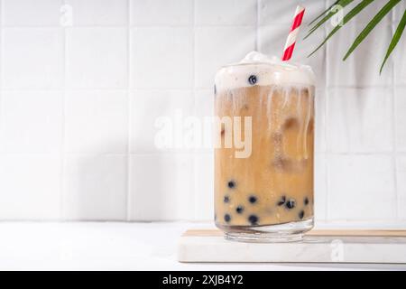 Classico boba bobble tea con perle di tapioca e crema non casearia montata sopra il bicchiere, dolce dolce dolce estivo su sfondo bianco della tavola c Foto Stock