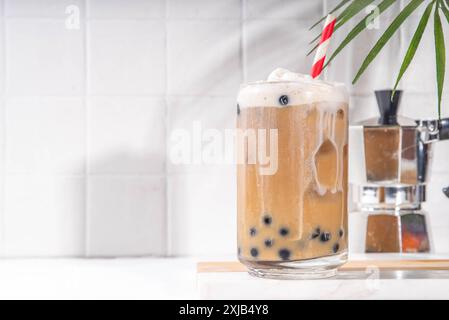 Classico boba bobble tea con perle di tapioca e crema non casearia montata sopra il bicchiere, dolce dolce dolce estivo su sfondo bianco della tavola c Foto Stock
