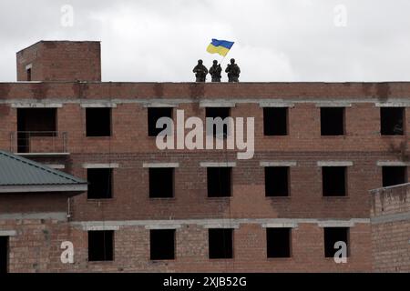 I soldati tengono la bandiera dell'Ucraina in cima all'edificio. liberazione dei territori. Guerra in Ucraina Foto Stock