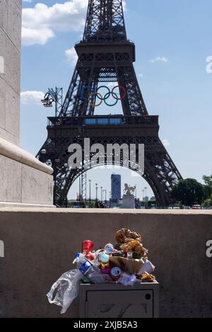 Un traboccante cestino su un marciapiede di fronte alla Torre Eiffel a Parigi Foto Stock