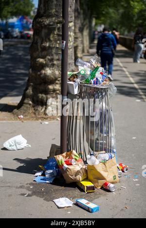 Parigi, Francia. Un bidone della spazzatura traboccante su un marciapiede vicino alla Senna. Foto Stock