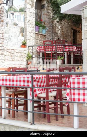 Tavoli e sedie in legno al caffè di strada nella piccola cittadina medievale che dona caldo giorno d'estate, non c'è gente Foto Stock