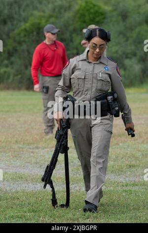 Florence Texas USA, 23 aprile 2024: Donna della polizia di stato del Dipartimento di pubblica sicurezza del Texas tiene la sua pistola tra un colpo e l'altro come parte della dodicesima competizione annuale Top Trooper. Gli ufficiali del DPS gareggiavano nella preparazione fisica, nel tiro, nella resistenza e nelle abilità di guida. Un totale di 120 soldati gareggiarono e ai due vincitori furono assegnati nuovi veicoli di pattuglia. ©Bob Daemmrich Foto Stock