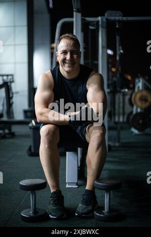 Uomo sorridente riposante dopo l'allenamento in una palestra moderna Foto Stock