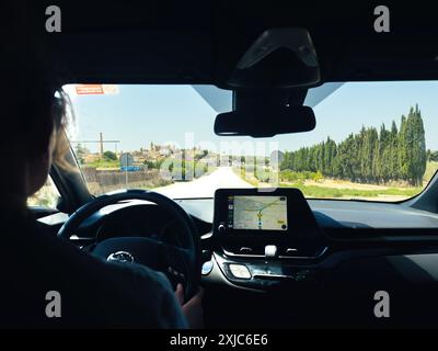 Arta, Spagna - 11 luglio 2024: Donna alla guida di una Toyota elettrica a Maiorca con Apple CarPlay visualizzato sullo schermo, che mostra una mappa e le istruzioni di navigazione Foto Stock