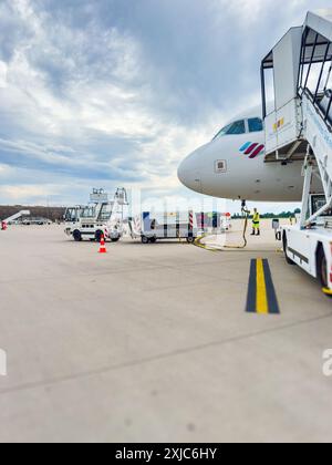 Baden, Baden - 11 luglio 2024: Aerei Eurowings presso l'aeroporto FKB Baden-Baden Karlsruhe, con scale mobili d'imbarco e attrezzature di servizio a terra visibili sull'asfalto sotto un cielo nuvoloso Foto Stock