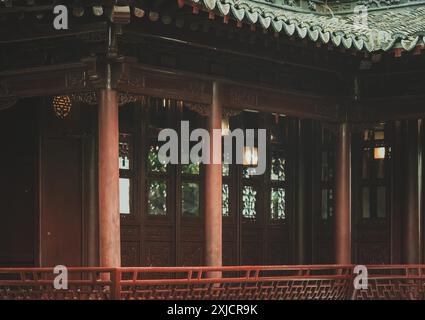 Una vista ravvicinata di una tradizionale struttura in legno cinese con dettagli intagliati e una ringhiera rossa. Foto Stock