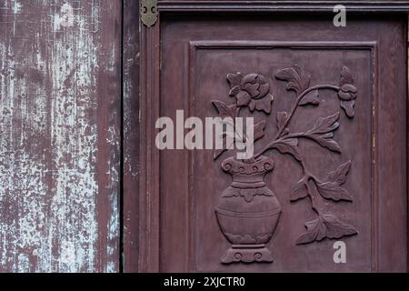 Shanghai, Cina - 06 giugno 2024: Intricate sculture in legno di fiori e un vaso su una porta intemprata nel Giardino Yu di Shanghai, Cina. Foto Stock