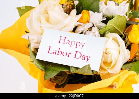 Immagine concettuale. Testo DEL GIORNO DEL LAVORO scritto in un bouquet con fiori su un biglietto bianco Foto Stock