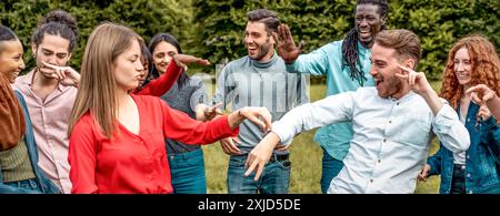 Allegri amici multietnici che si divertono insieme nella natura. Gruppo di giovani adulti che ridono e giocano all'aperto, mostrando amicizia e unità Foto Stock