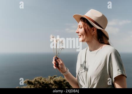 Giovane donna con un cappello che ammira i Dandelions Foto Stock