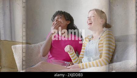 Immagine del film su due ragazze adolescenti felici e diverse che guardano film con popcorn a casa Foto Stock