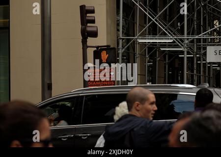 5th Avenue, i pedoni di New York aspettano di attraversare un incrocio con un segnale di FERMATA, passa un'auto nera, un cartello con scritto "We buy Gold & Diamond" ponteggio Foto Stock