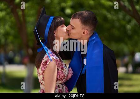 Giovane laureato universitario in insegne accademiche e cap con la sua fidanzata che celebra il momento Foto Stock