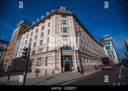 Londra, Regno Unito - 09 ottobre 2023: Un edificio ad angolo a Londra con un autobus rosso a due piani che passa per la strada. Foto Stock