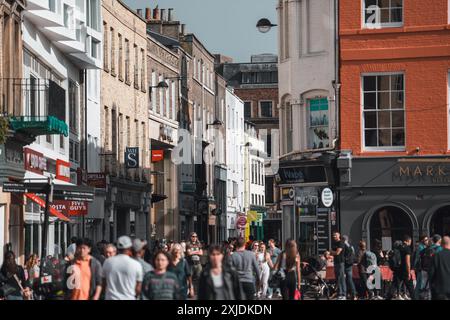 Cambridge, Regno Unito - 8 ottobre 2023: Una scena di strada affollata a Cambridge, Regno Unito, fiancheggiata da edifici in mattoni e negozi. Gli edifici presentano un mix di bianco Foto Stock