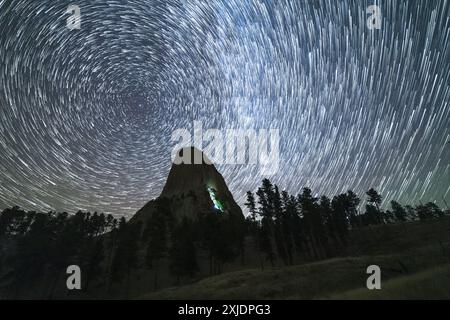 Star Trails sul Devils Tower Butte di notte. Luce di scalatori su un muro. Wyoming, Stati Uniti Foto Stock